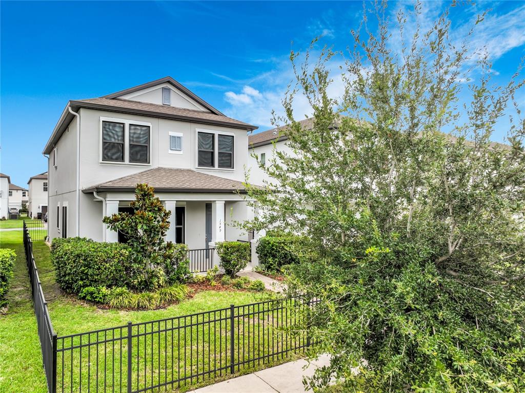 A two-story house with a light-colored exterior, a front porch, and a black metal fence — 1549 ASTORIA ARBOR LANE, ORLANDO, FL
