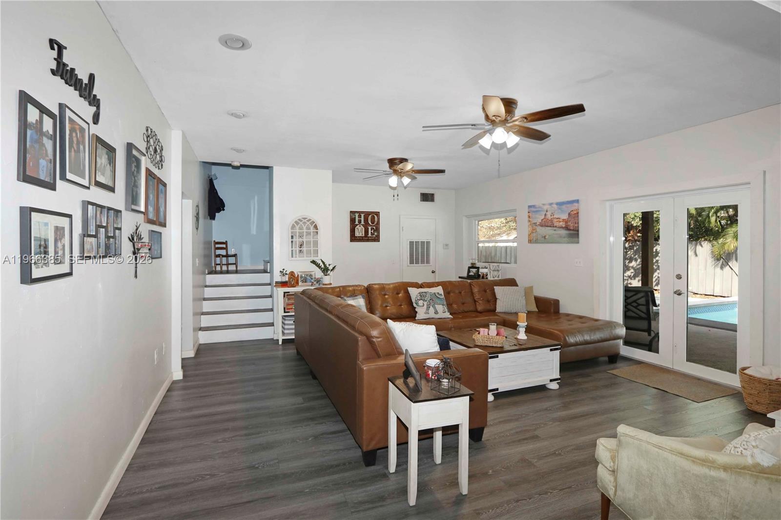 A living room features a brown leather sectional, gray wood-look flooring, and a pool view — 1221 SW 74th Ct, Miami FL 33144, MIAMI, FL