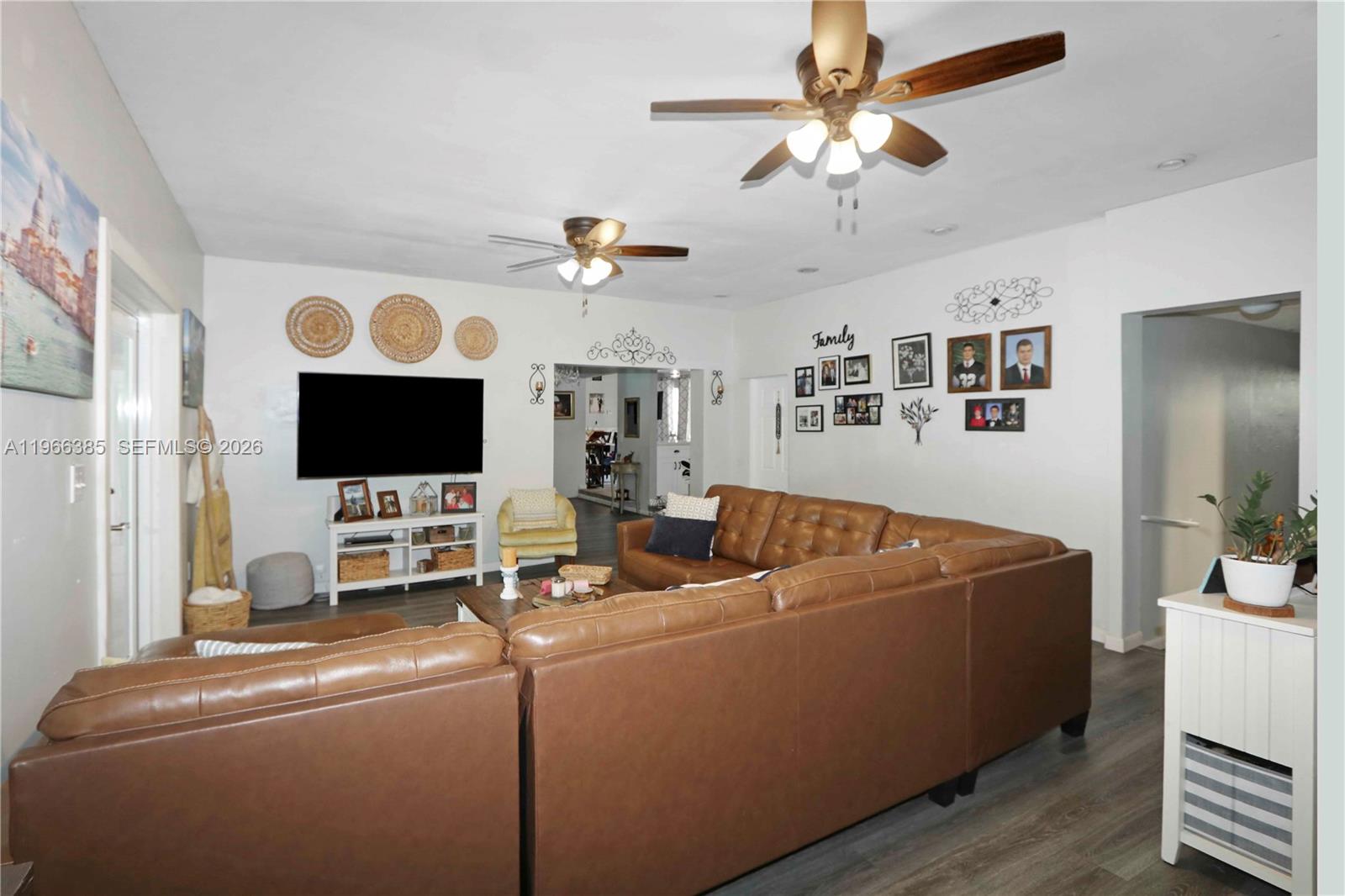 A living room features a large brown leather sectional, a television, and two ceiling fans — 1221 SW 74th Ct, Miami FL 33144, MIAMI, FL