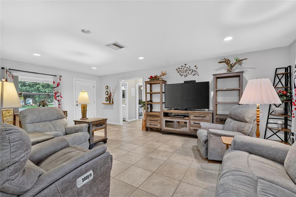 A living room features gray reclining furniture, tile flooring, and a television on a stand — 37414 TURNER DRIVE, UMATILLA, FL