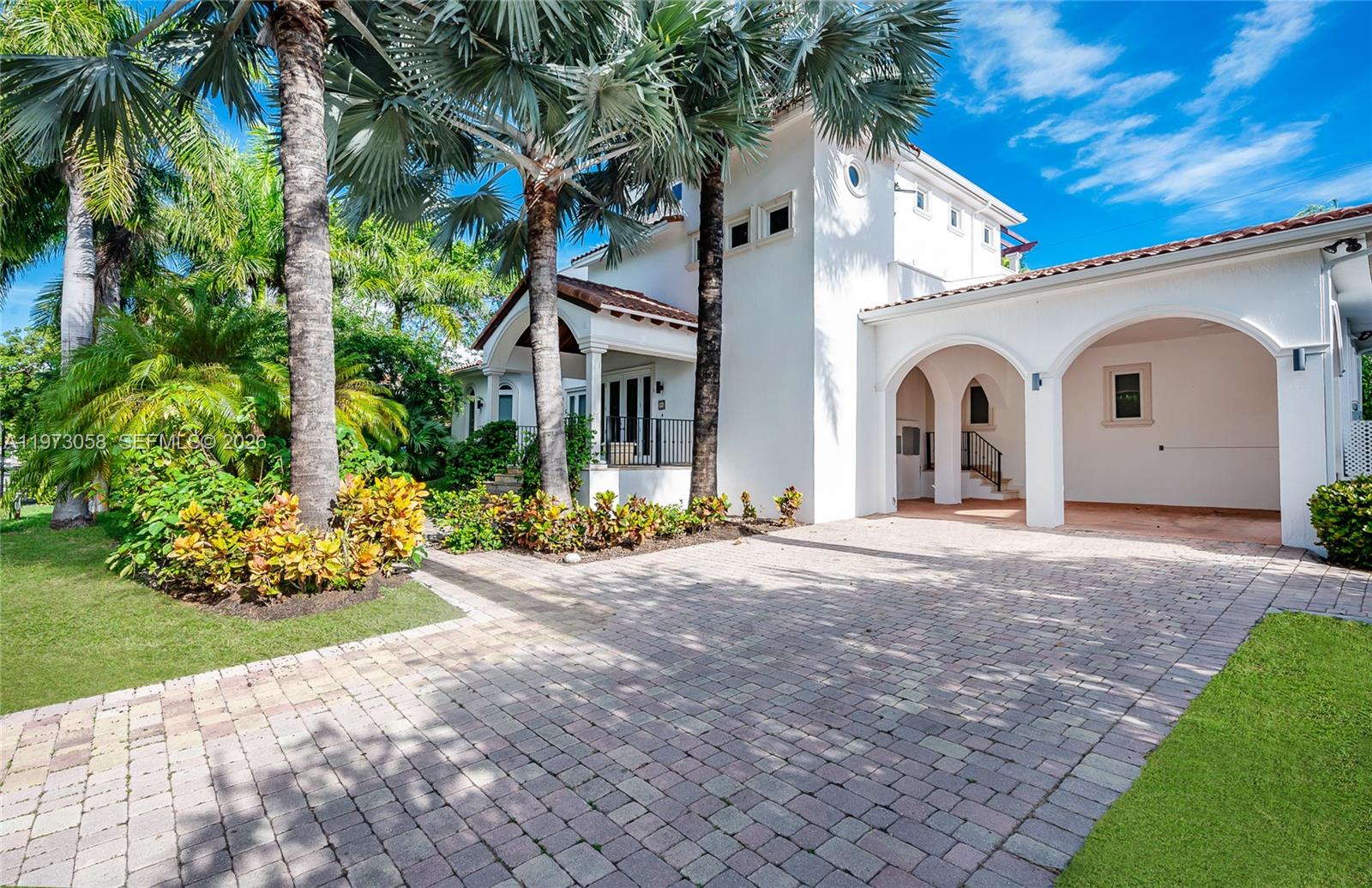 A white two-story house with a paved driveway, arched portico, and surrounding palm trees — 541 S Mashta Dr, Key Biscayne FL 33149, KEY BISCAYNE, FL