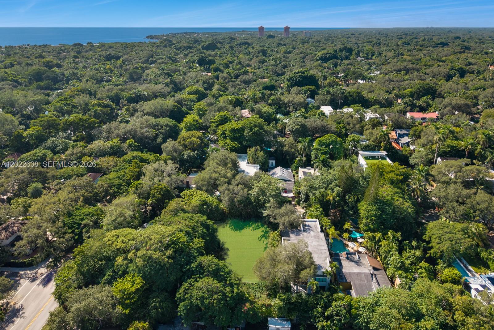 An aerial view shows a house with a green lawn and pool amidst dense trees — 3729 Kumquat Ave, Miami FL 33133, MIAMI, FL