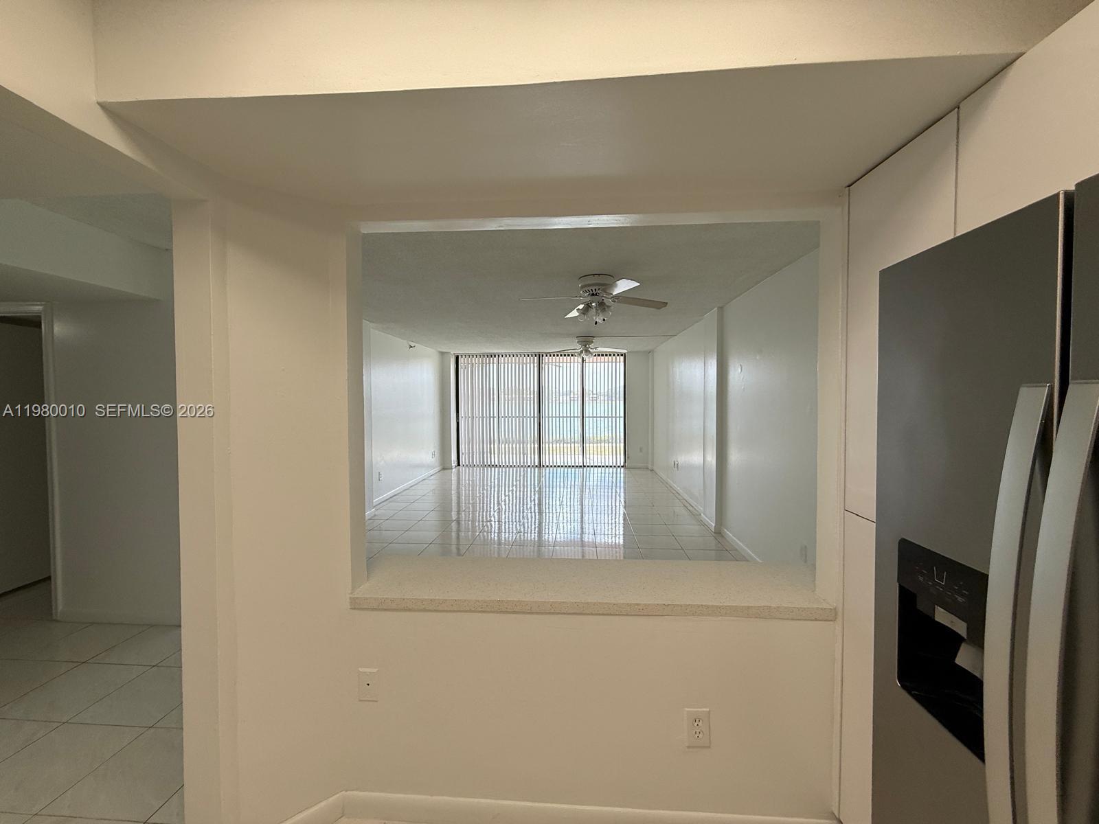 A kitchen pass-through window looks into a tiled living area with floor-to-ceiling blinds — 20850 San Simeon Way # 5, Miami FL 33179, MIAMI, FL