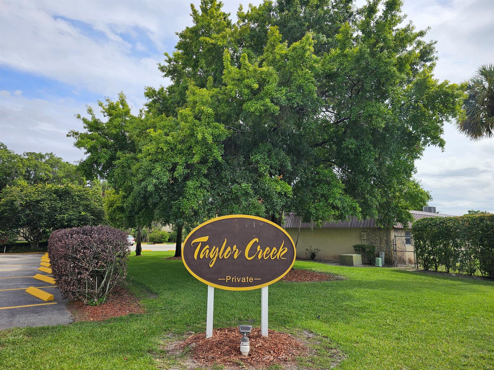 A brown oval sign for Taylor Creek stands in a grassy area near a parking lot — 3124 SE Us Highway 441 # J8, Okeechobee FL 34974, OKEECHOBEE, FL
