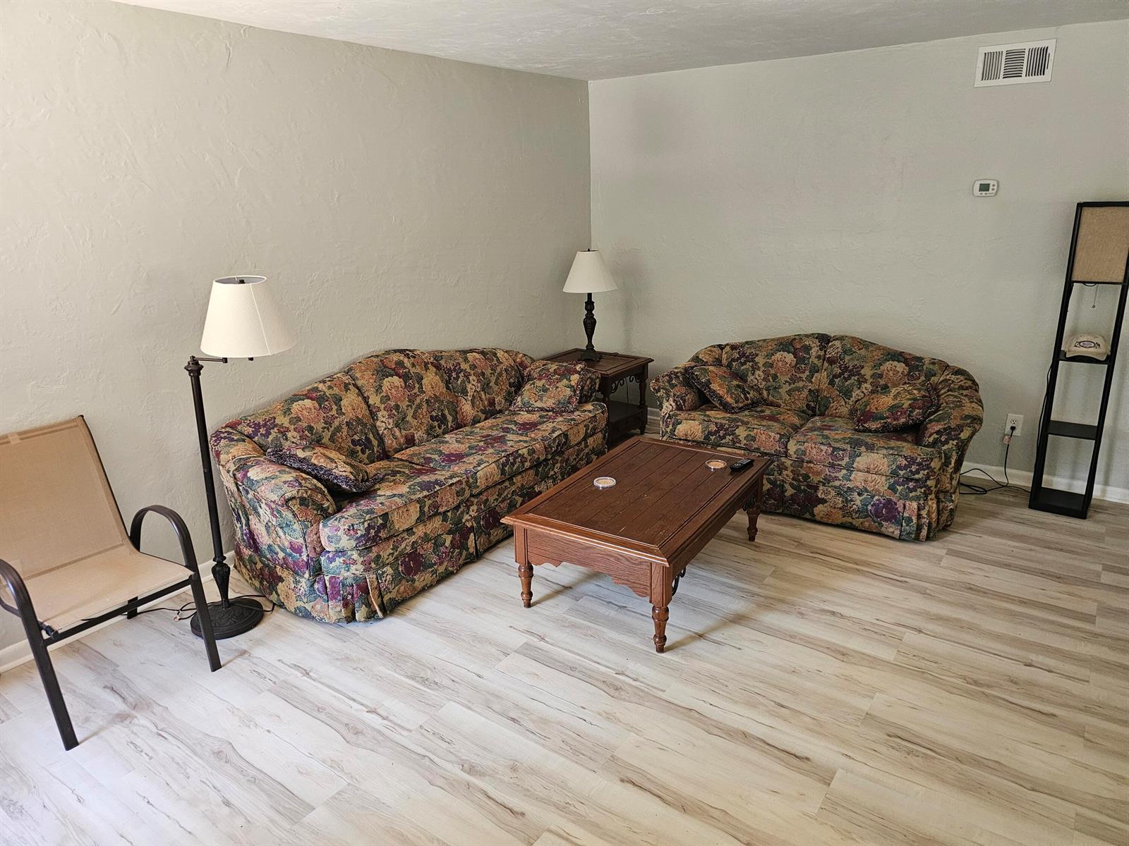 A living room features two floral sofas, a wooden coffee table, and light wood-look flooring — 3124 SE Us Highway 441 # J8, Okeechobee FL 34974, OKEECHOBEE, FL