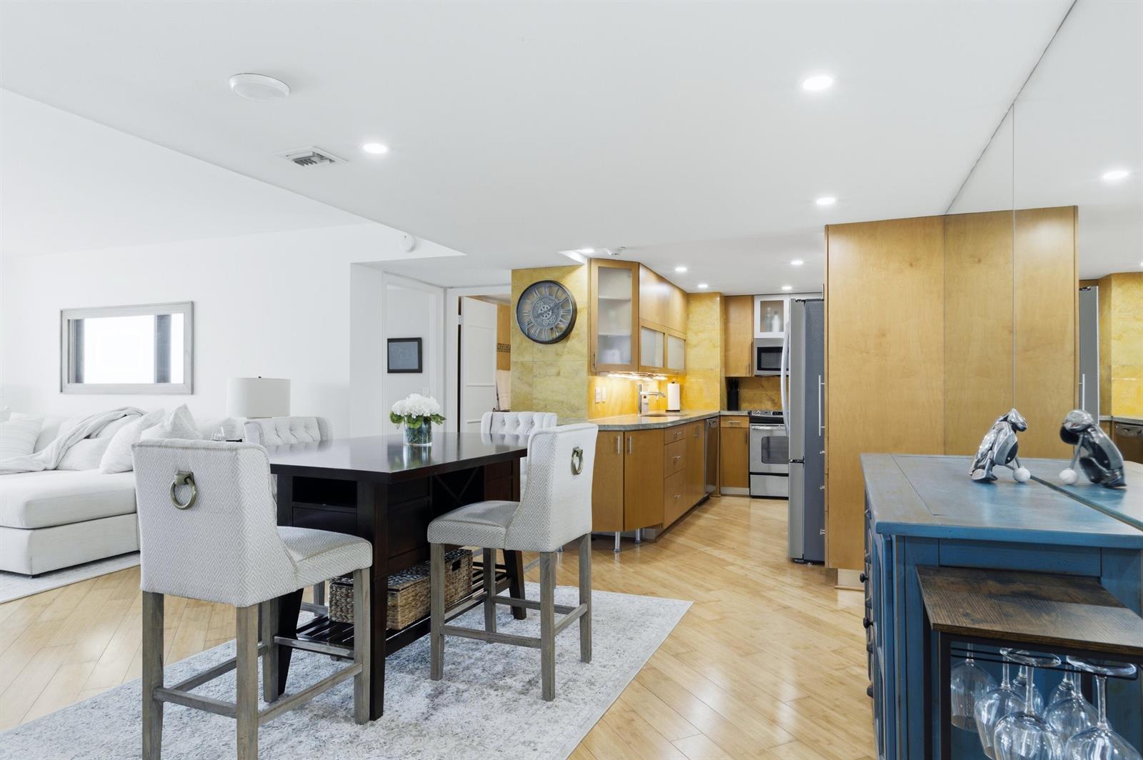 An open-concept kitchen and dining area features light wood flooring and modern cabinetry — 5600 N Flagler Drive Unit 910, West Palm Beach FL 33407, WEST PALM BEACH, FL