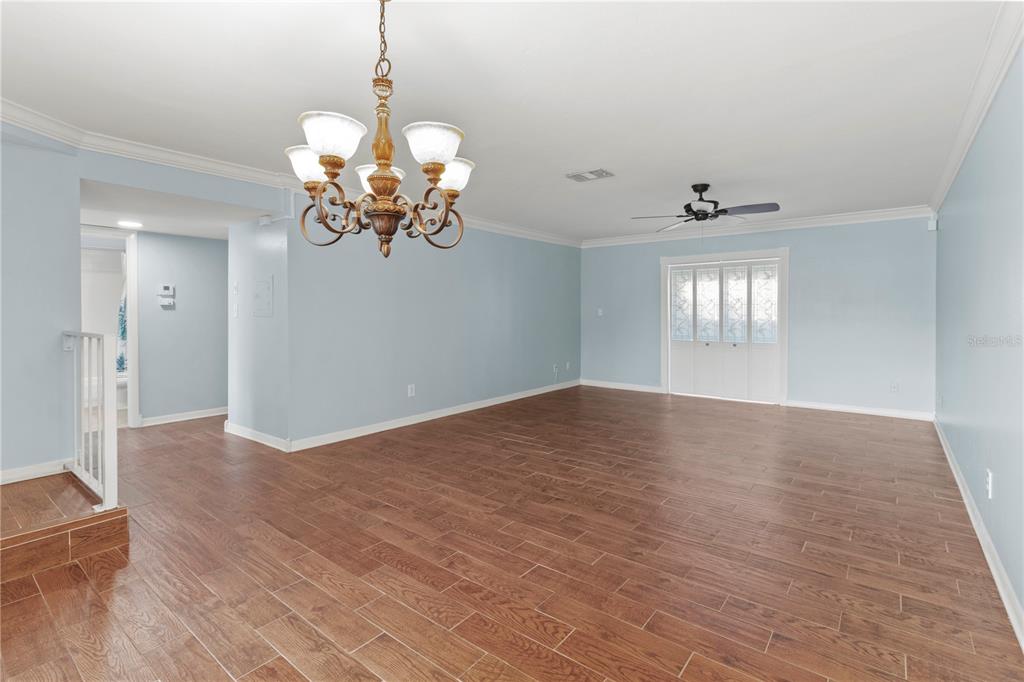 A spacious room with light blue walls, wood-look tile flooring, a chandelier, and a ceiling fan — 1446 56TH STREET W UNIT 1446, BRADENTON, FL