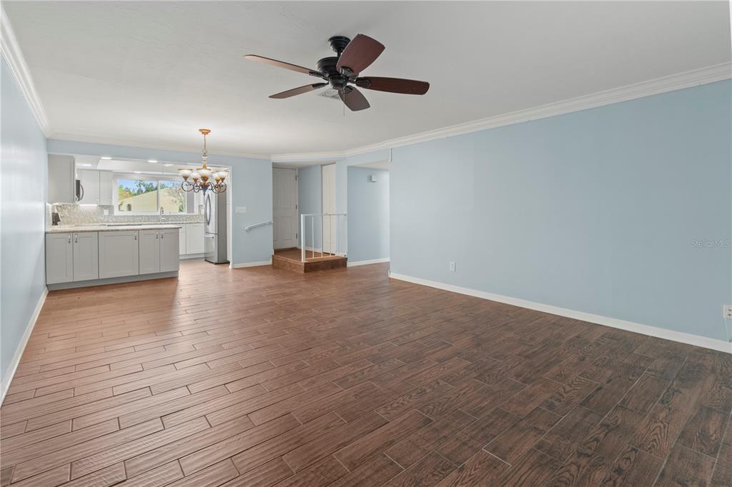 An open-concept living area features light blue walls, wood-look tile flooring, and a ceiling fan — 1446 56TH STREET W UNIT 1446, BRADENTON, FL