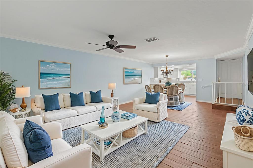 A living room features white furniture, blue accents, and wood-look tile flooring — 1446 56TH STREET W UNIT 1446, BRADENTON, FL