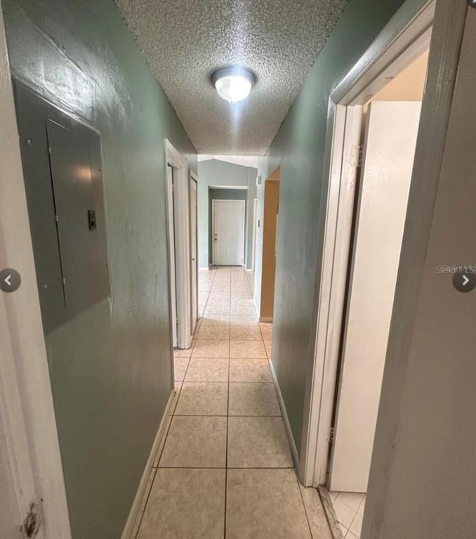 A hallway with light green walls, tiled flooring, and a ceiling-mounted light fixture — 5213 VIA HACIENDA CIRCLE UNIT 308, ORLANDO, FL