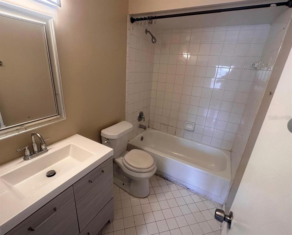 A bathroom features a vanity with a white sink, a toilet, and a tiled tub-shower — 5213 VIA HACIENDA CIRCLE UNIT 308, ORLANDO, FL