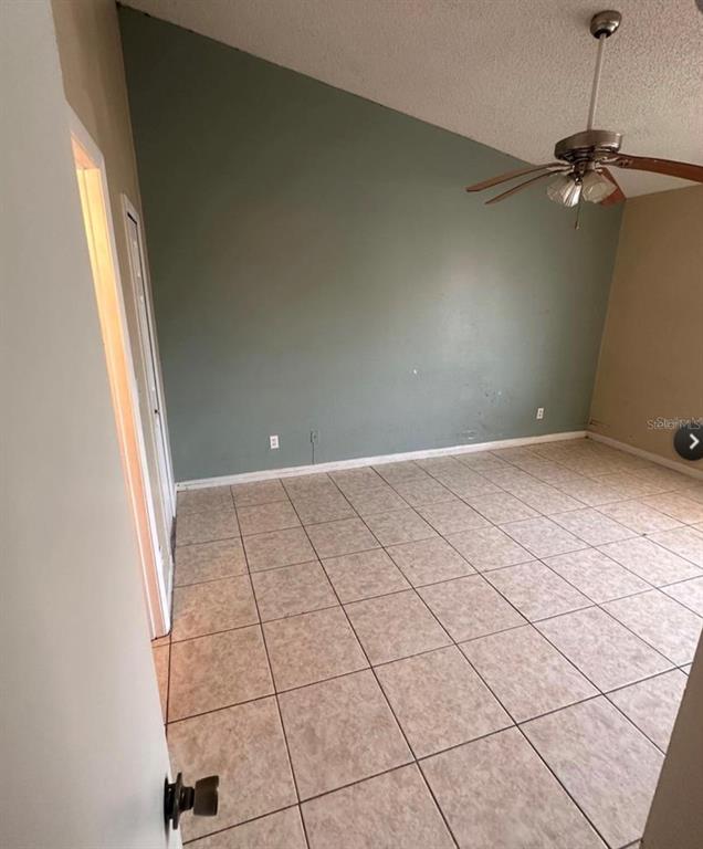 An empty room features a vaulted ceiling, a ceiling fan, and light-colored tile flooring — 5213 VIA HACIENDA CIRCLE UNIT 308, ORLANDO, FL
