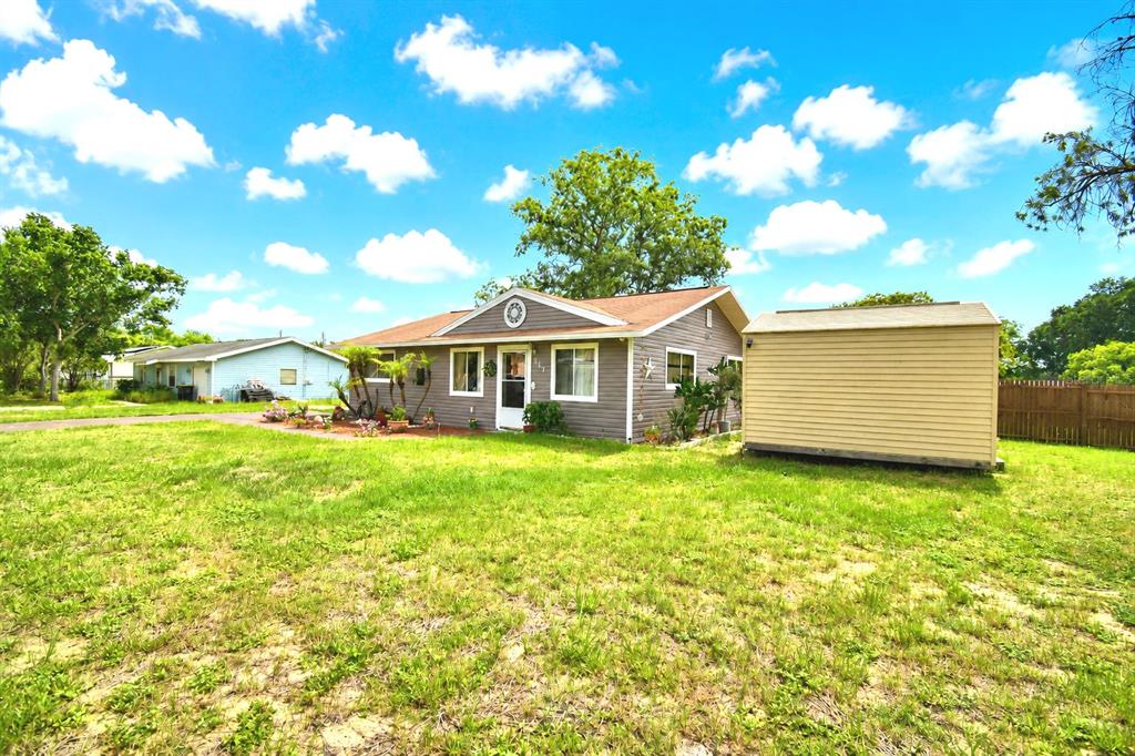 A single-story house with gray siding and a shed sits on a grassy lot — 142 MARTHA DRIVE, LAKE WALES, FL