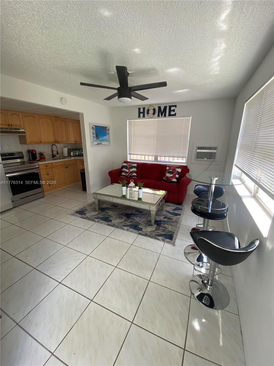 A kitchen and living area features tile floors, a red sofa, and a glass dining table — 3210 Canal Dr # 8, Pompano Beach FL 33062, POMPANO BEACH, FL