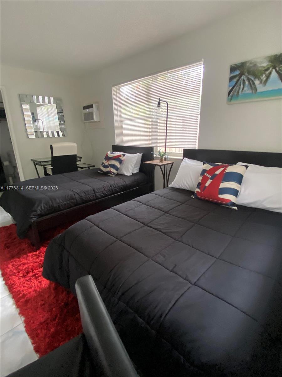 A bedroom features two beds with black bedding, a red rug, and a window — 3210 Canal Dr # 8, Pompano Beach FL 33062, POMPANO BEACH, FL