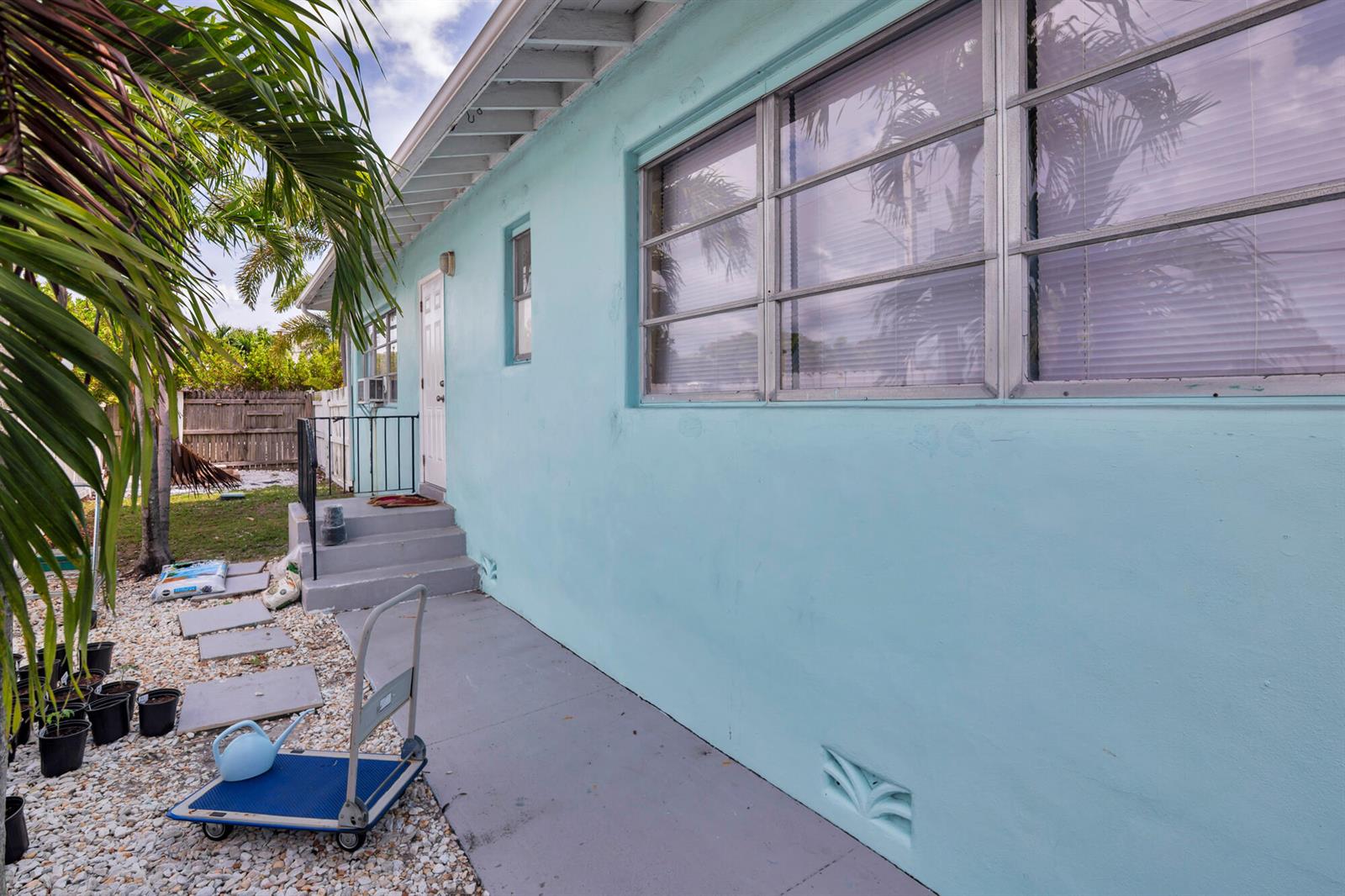 A light blue exterior wall of a house features a white door and large windows — 258 Conniston Road, West Palm Beach FL 33405, WEST PALM BEACH, FL