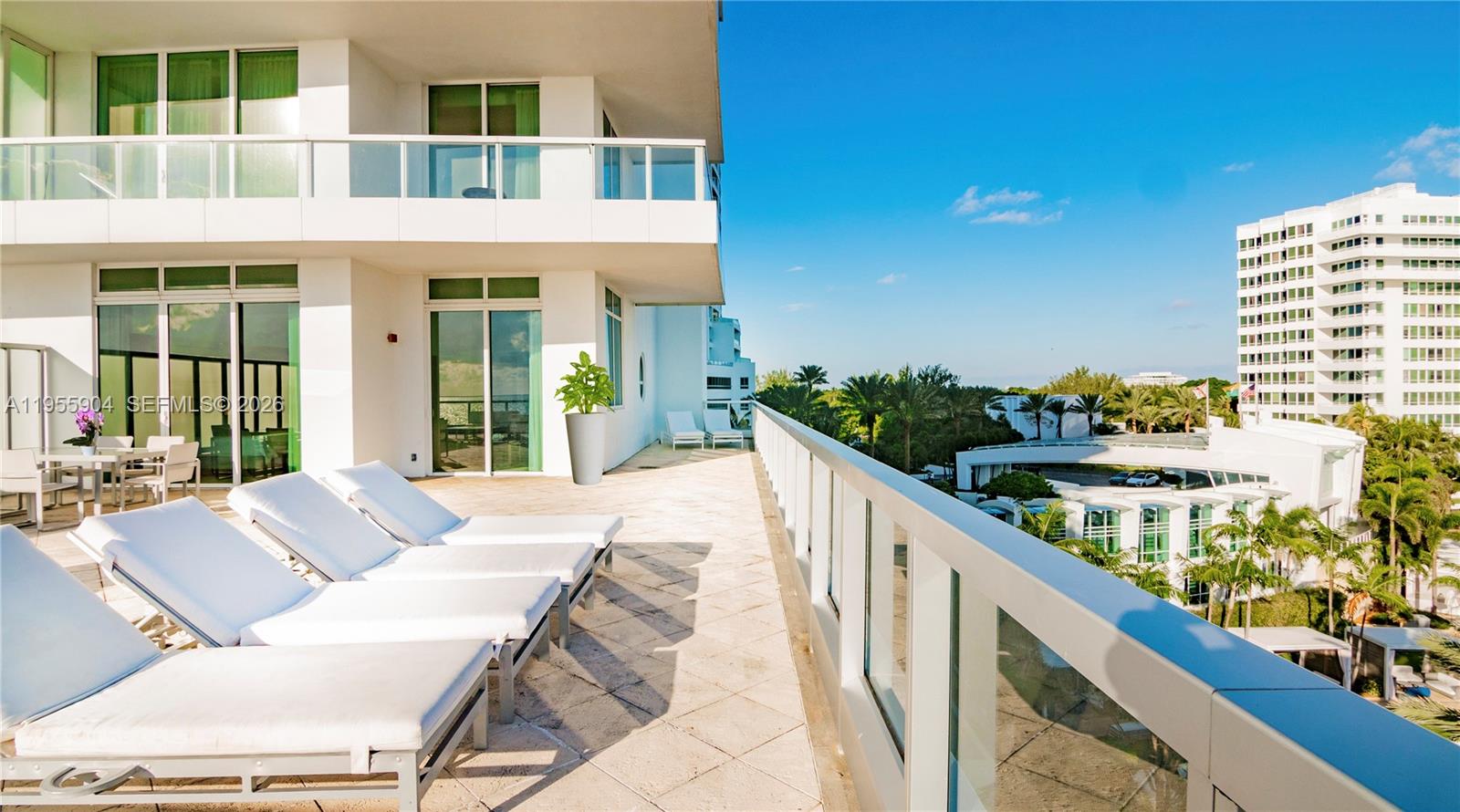 A spacious outdoor terrace features white lounge chairs, glass railings, and views of surrounding buildings — 4391 Collins Ave, Miami Beach FL 33140, MIAMI BEACH, FL