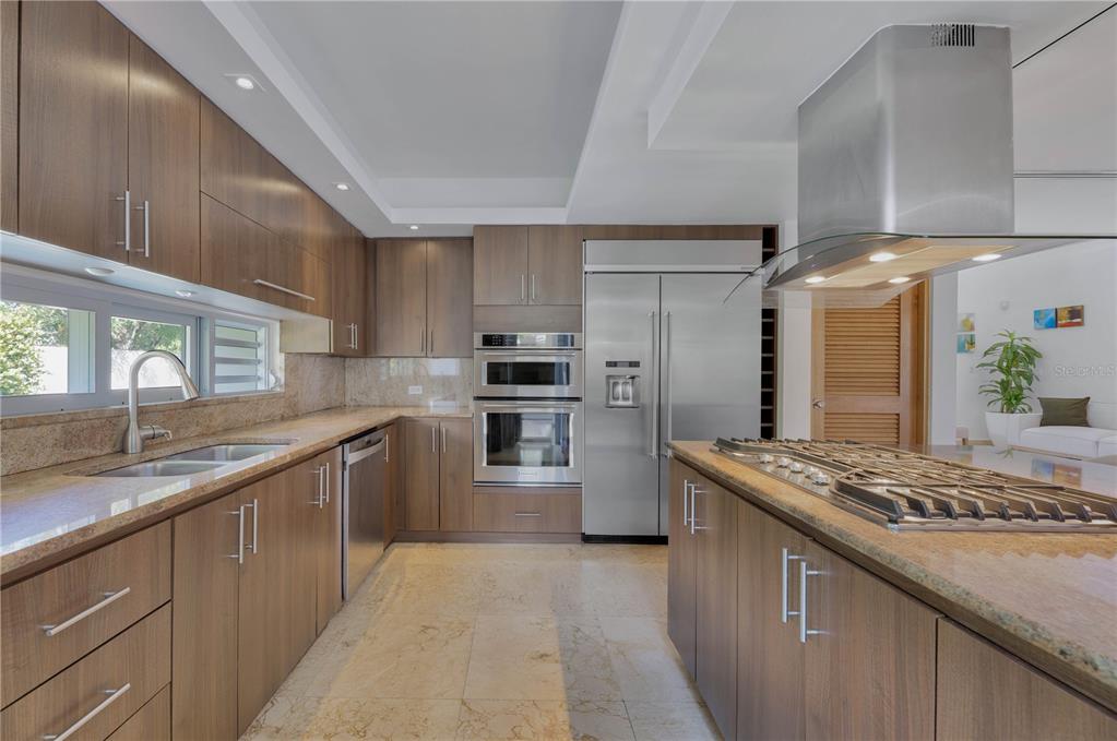 A modern kitchen features wood cabinets, stainless steel appliances, a center island, and stone countertops — 2200 CACIQUE STREET, SAN JUAN, PR
