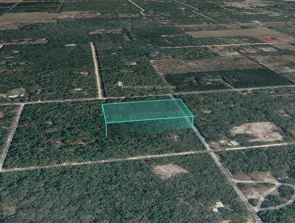 An aerial map view shows a rectangular plot of land highlighted in blue — NW 85TH AVENUE, CHIEFLAND, FL