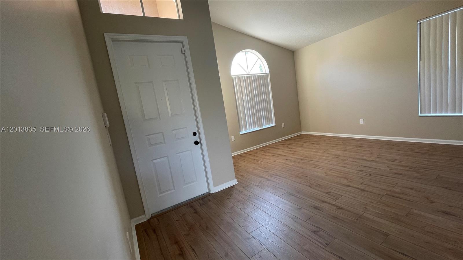An empty room features light wood-look flooring, beige walls, and two windows with vertical blinds — 18811 SW 29th Ct, Miramar FL 33029, MIRAMAR, FL