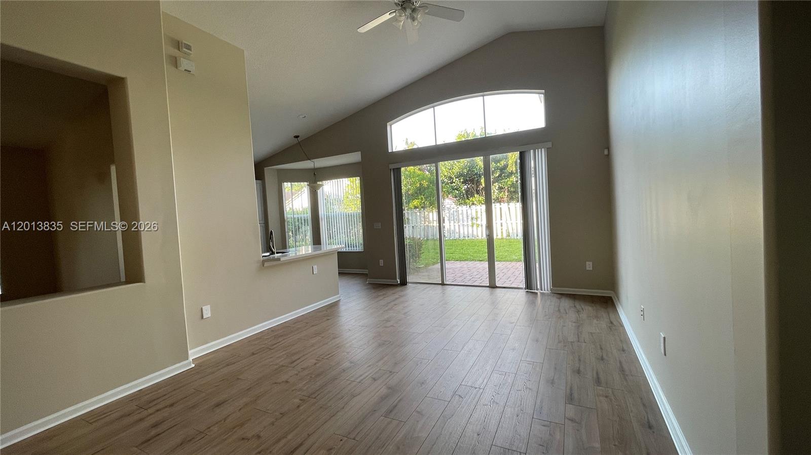 A living room with vaulted ceilings, wood-look flooring, and sliding glass doors to a patio — 18811 SW 29th Ct, Miramar FL 33029, MIRAMAR, FL