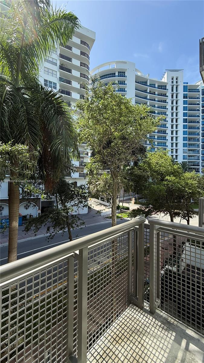 A view from a balcony overlooking a street, trees, and several high-rise apartment buildings — 6000 Collins Ave # 323, Miami Beach FL 33140, MIAMI BEACH, FL