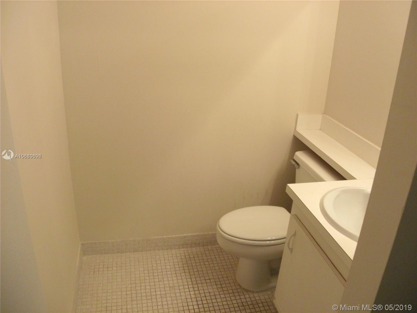 A small bathroom features a white toilet, a vanity with a sink, and tiled flooring — 4174 Inverrary Dr # 911, Lauderhill FL 33319, LAUDERHILL, FL