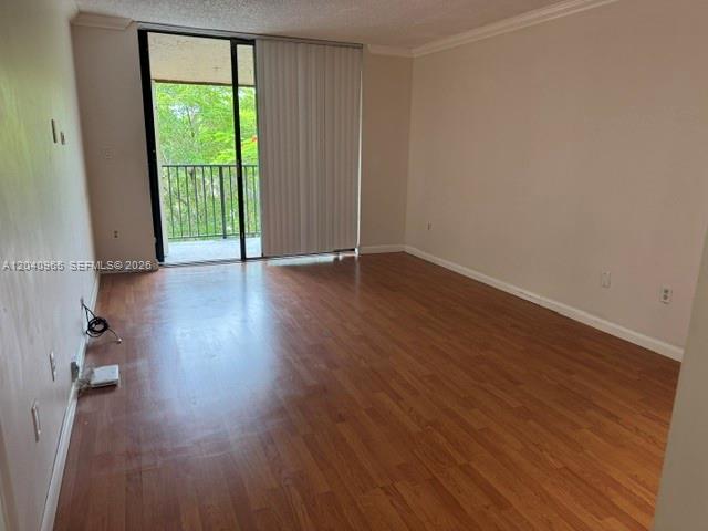 An empty room features wood-look flooring, beige walls, and a sliding glass door to a balcony — 14321 N Kendall Dr # 403F, Miami FL 33186, MIAMI, FL