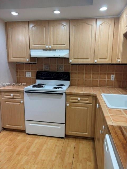A kitchen features light wood cabinets, a white stove, and brown tiled backsplashes — 14321 N Kendall Dr # 403F, Miami FL 33186, MIAMI, FL