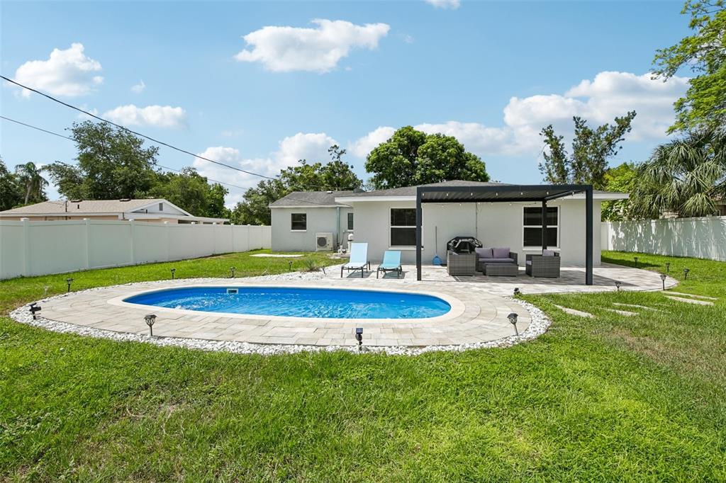 A backyard features a swimming pool, a paved patio with a pergola, and white fencing — 2214 23RD AVENUE W, BRADENTON, FL