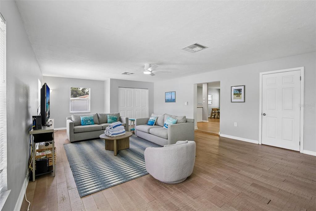 A living room features gray sofas, a striped rug, wood flooring, and a ceiling fan — 2214 23RD AVENUE W, BRADENTON, FL