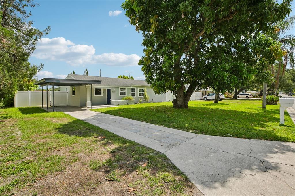 A single-story house with a carport, a paved walkway, and a large tree in front — 2214 23RD AVENUE W, BRADENTON, FL