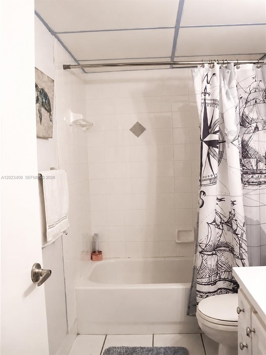 A bathroom features a white tiled bathtub and shower area with a nautical-themed shower curtain — 500 NE 2nd St # 115, Dania Beach FL 33004, DANIA BEACH, FL
