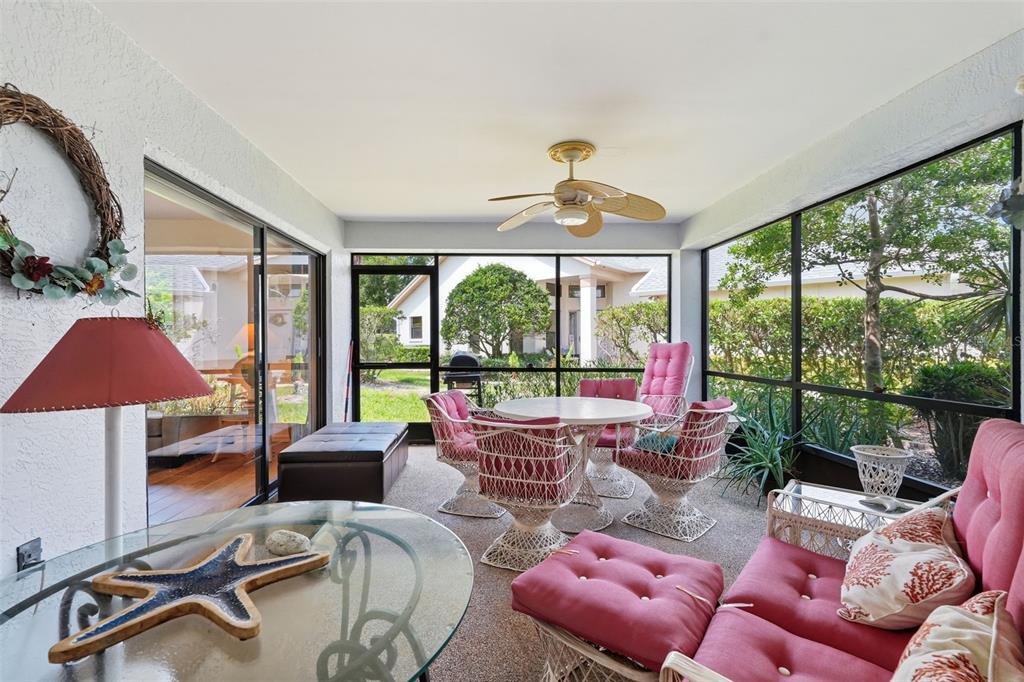 A sunroom features a glass-topped table, pink cushioned seating, a ceiling fan, and screened walls — 3254 LORI LANE, NEW PORT RICHEY, FL