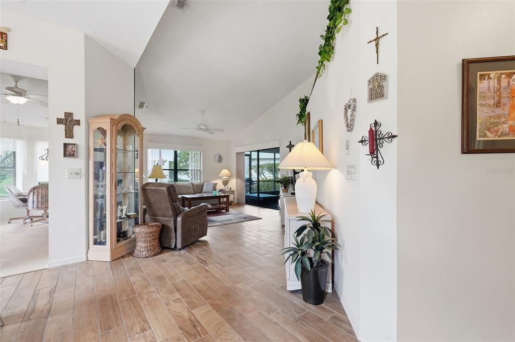 A living room with vaulted ceilings, tile flooring, and a glass display cabinet — 3254 LORI LANE, NEW PORT RICHEY, FL