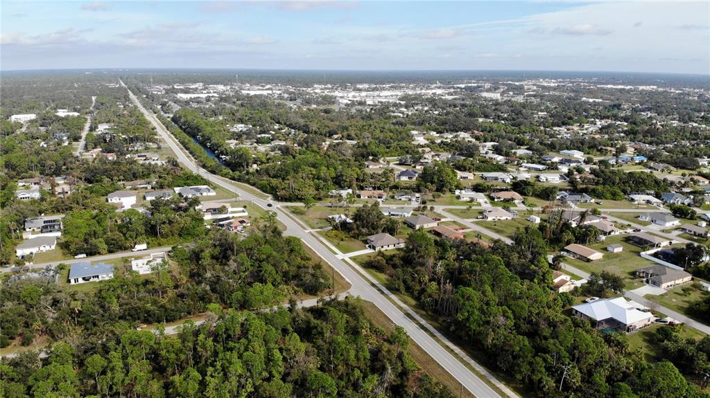An aerial view shows a residential neighborhood with houses scattered among trees and paved roads — 17497 BILLIAR AVENUE, PORT CHARLOTTE, FL