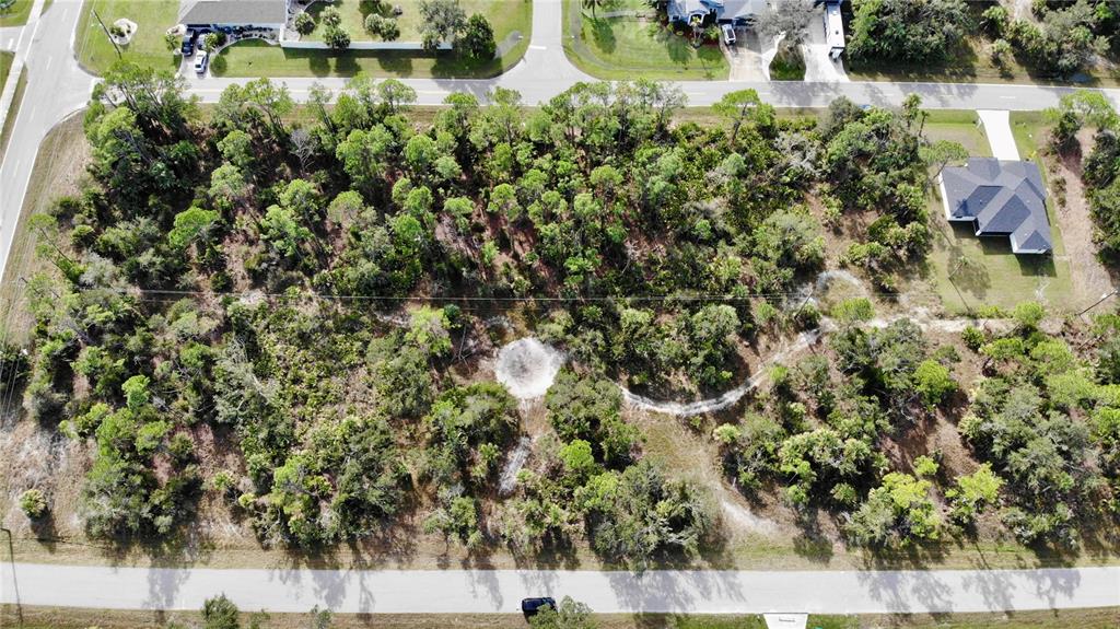 An aerial view shows a rectangular, wooded vacant lot situated between two paved roads — 17497 BILLIAR AVENUE, PORT CHARLOTTE, FL
