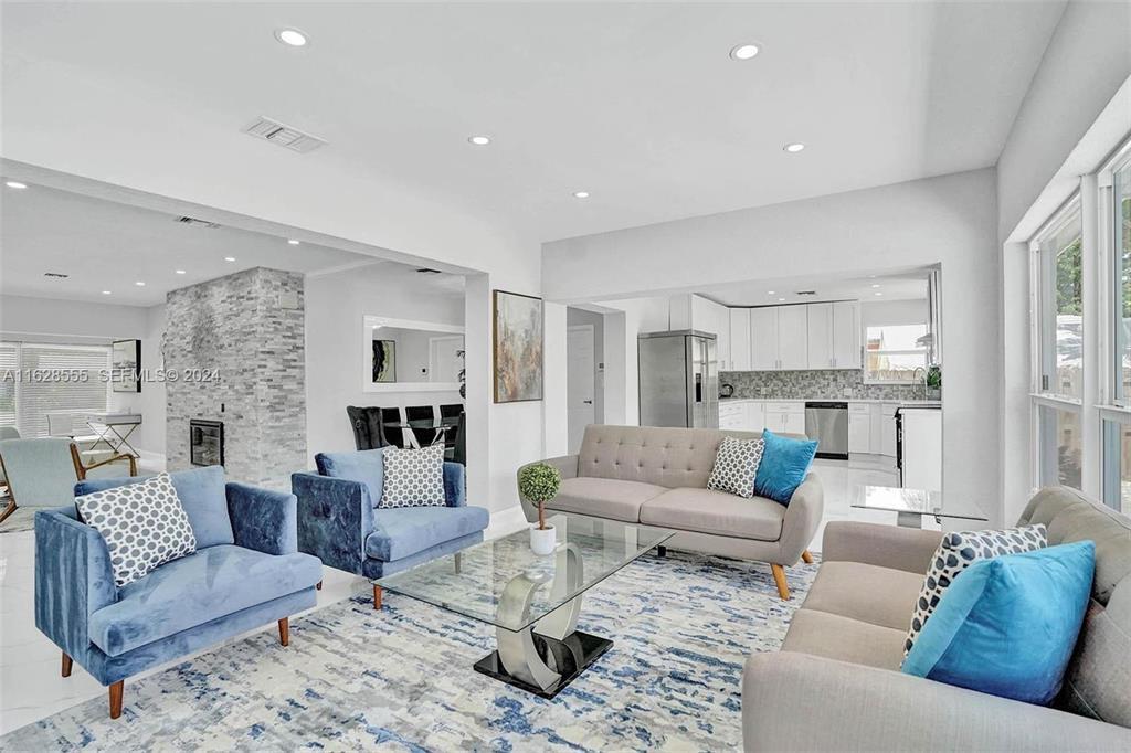 A living room with blue and gray furniture, a glass coffee table, and stone fireplace — 3421 Dover Road, Pompano Beach FL 33062, POMPANO BEACH, FL
