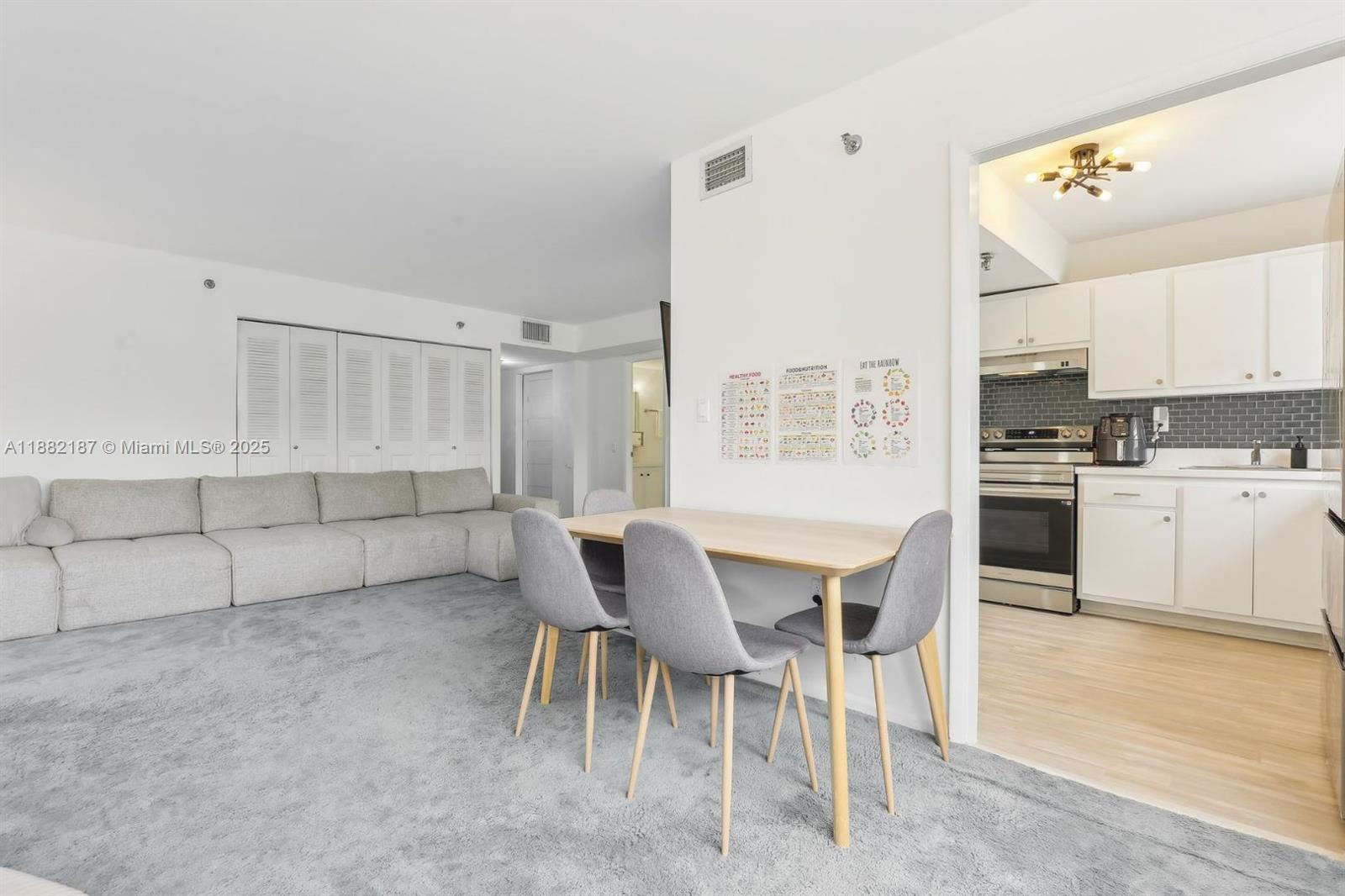 A dining area with a table and chairs sits between a carpeted living room and kitchen — 1345 West Avenue # 304, Miami Beach FL 33139, MIAMI BEACH, FL