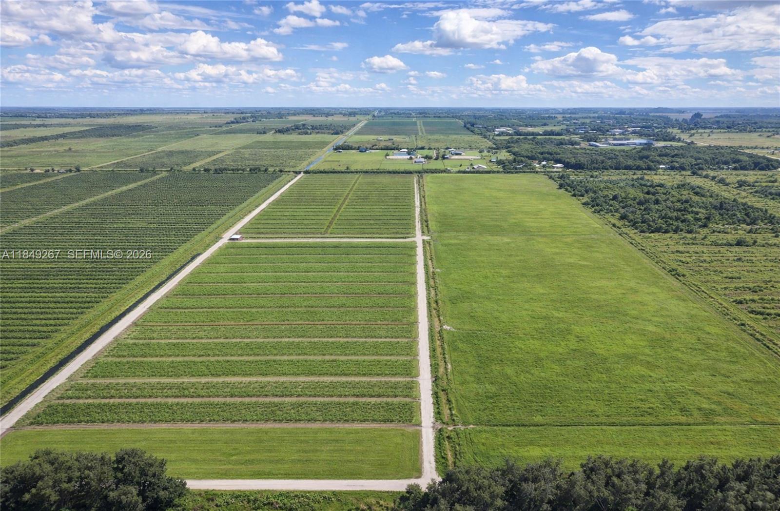 An aerial view shows large agricultural fields divided by dirt roads under a cloudy sky — 595 N HEADER CANAL ROAD, Fort Pierce FL 34945, FORT PIERCE, FL