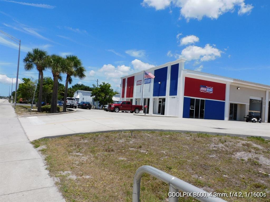 A commercial building with red and blue exterior paint features a parking lot and palm trees — 23278 HARBORVIEW ROAD, PUNTA GORDA, FL