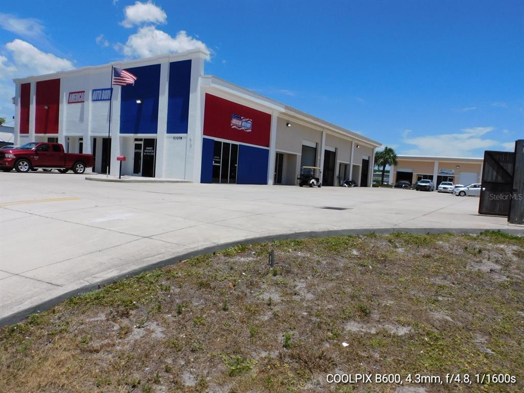 A commercial building with red, white, and blue exterior paint features a large parking lot — 23278 HARBORVIEW ROAD, PUNTA GORDA, FL