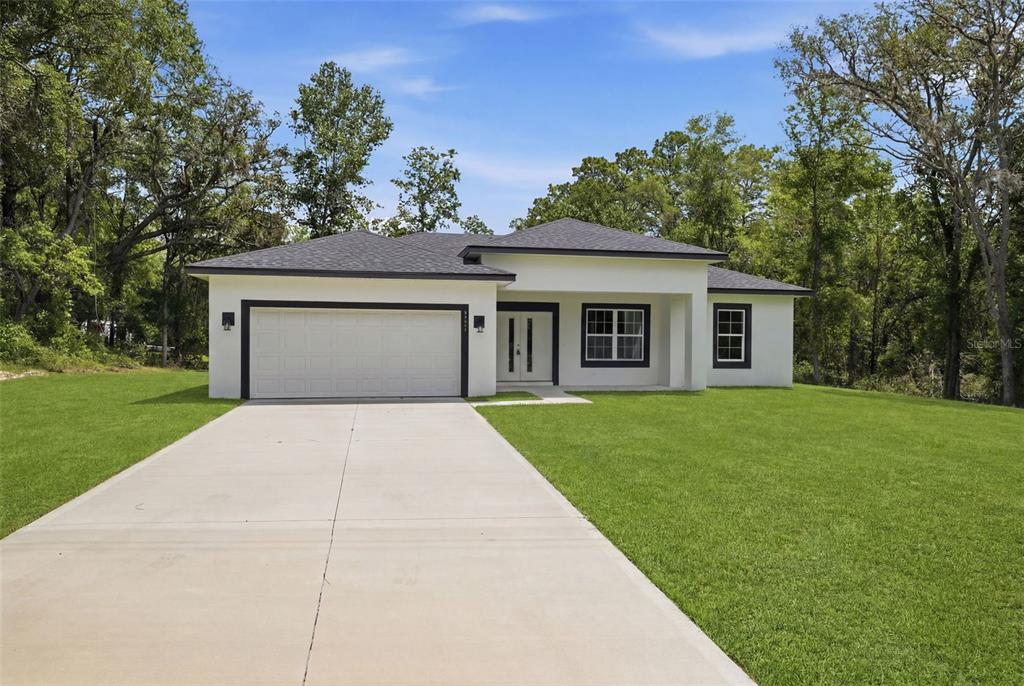 A single-story white house with a two-car garage and a concrete driveway — 8511 N GOLFVIEW DRIVE, CITRUS SPRINGS, FL