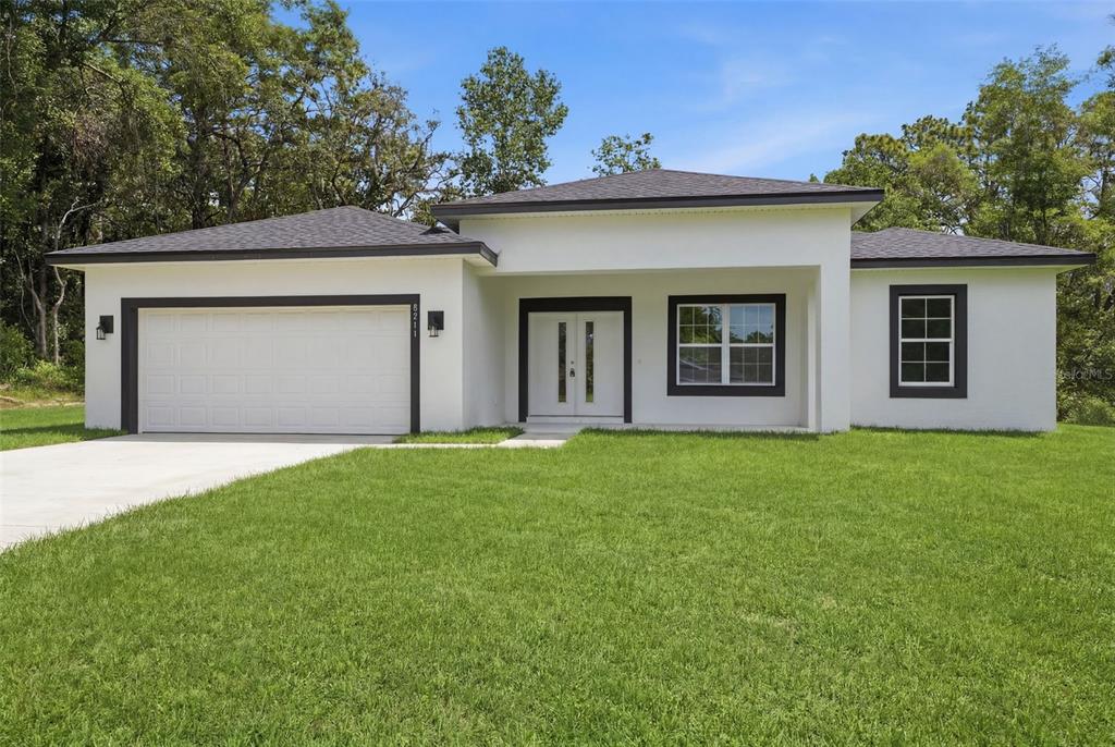 A single-story house with white stucco walls, a dark roof, and a two-car garage — 8511 N GOLFVIEW DRIVE, CITRUS SPRINGS, FL