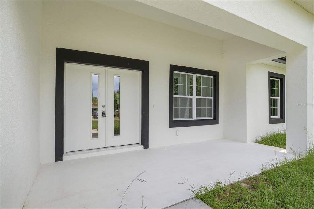 A covered porch features a white double front door and windows with dark trim — 8511 N GOLFVIEW DRIVE, CITRUS SPRINGS, FL