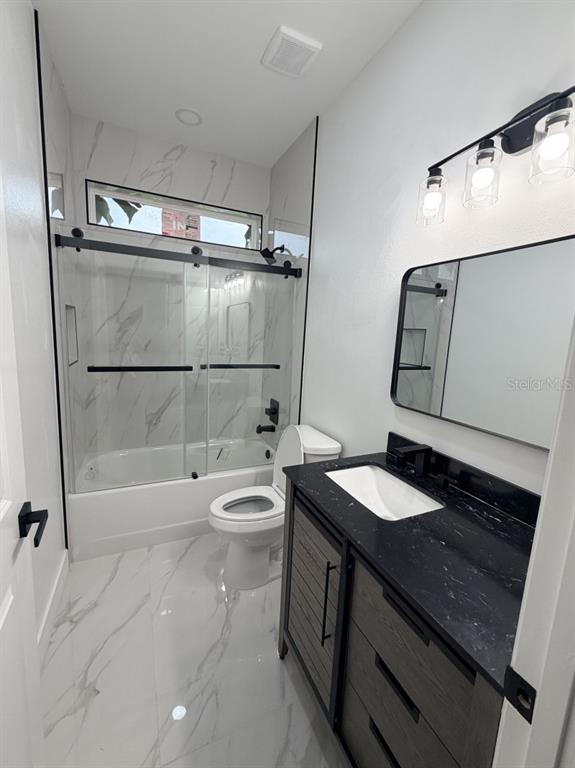 A modern bathroom features a marble-tiled shower, a black vanity, and a black-framed mirror — 3500 SE 484, BELLEVIEW, FL