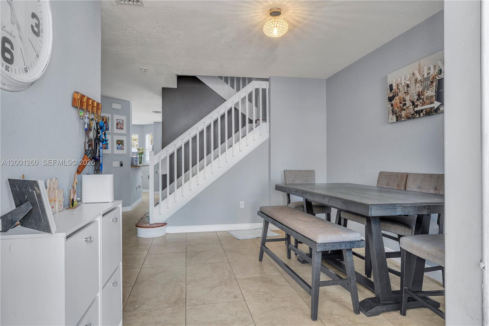A dining area features a wooden table with a bench and chairs near a staircase — 1024 NE 208th St, Miami FL 33179, MIAMI, FL