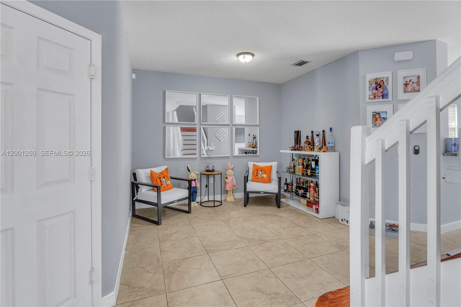 A seating area features two chairs, a small table, a bar unit, and wall mirrors — 1024 NE 208th St, Miami FL 33179, MIAMI, FL