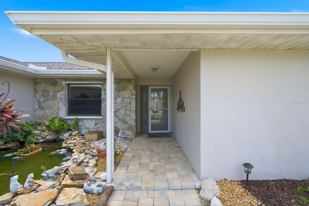A stone-accented house exterior features a paved walkway leading to a glass-paned front door — 9903 SAN SEBASTIAN WAY, PORT RICHEY, FL