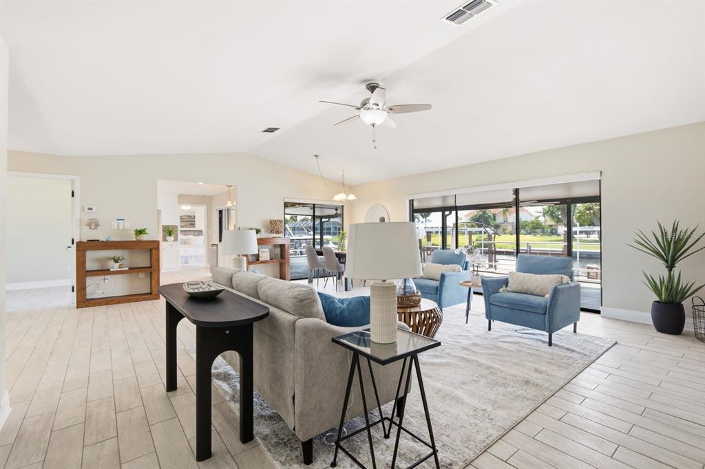 A bright living room features light tile floors, a gray sofa, and blue armchairs — 9903 SAN SEBASTIAN WAY, PORT RICHEY, FL
